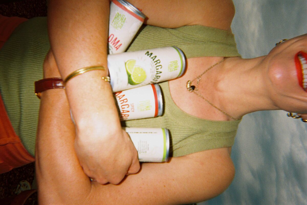 A guest carrying an armful of Doña Fuego Paloma and Margarita cans