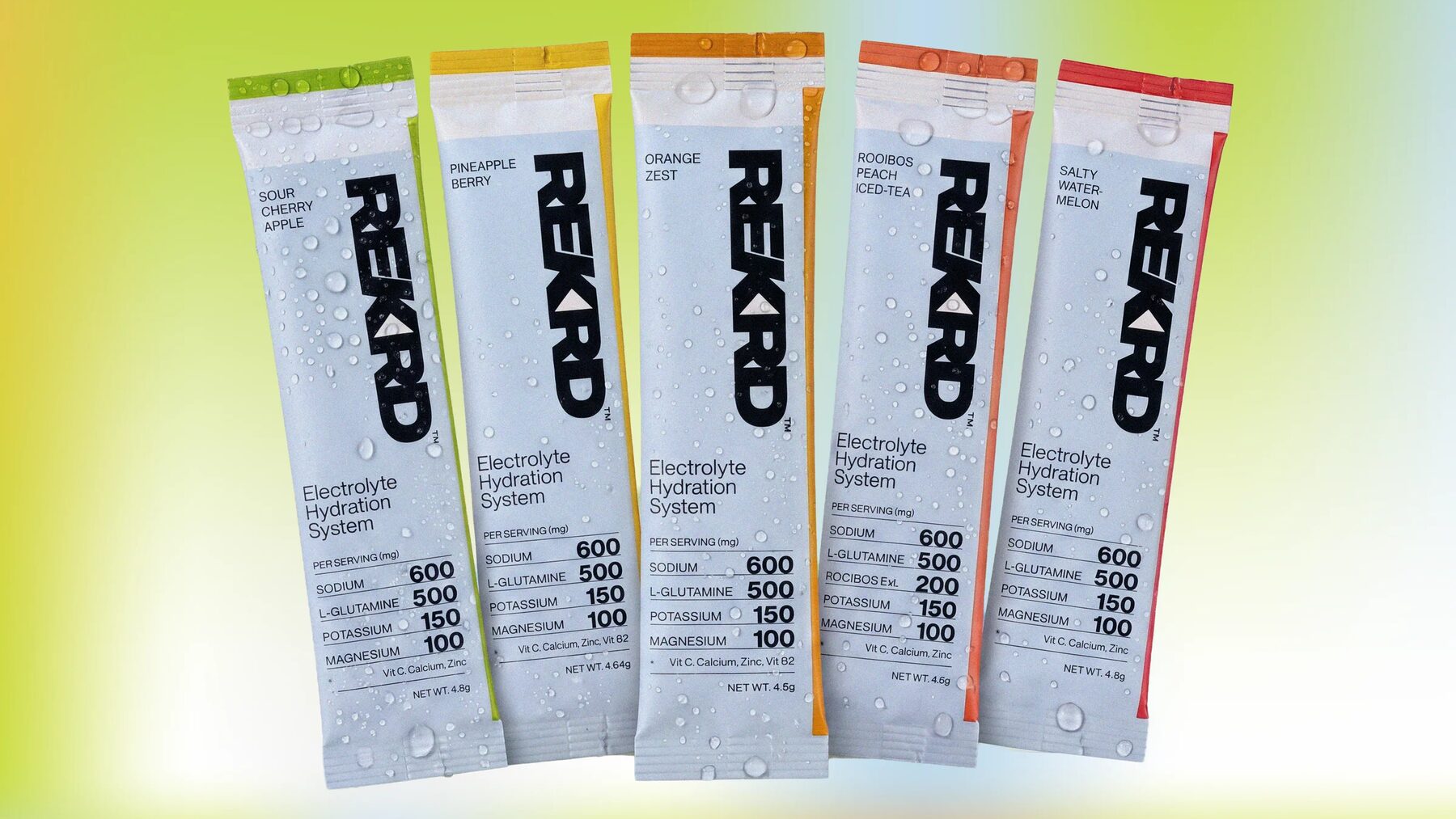 Five REKRD electrolyte sachets fanned out, beaded with water, one for each flavour