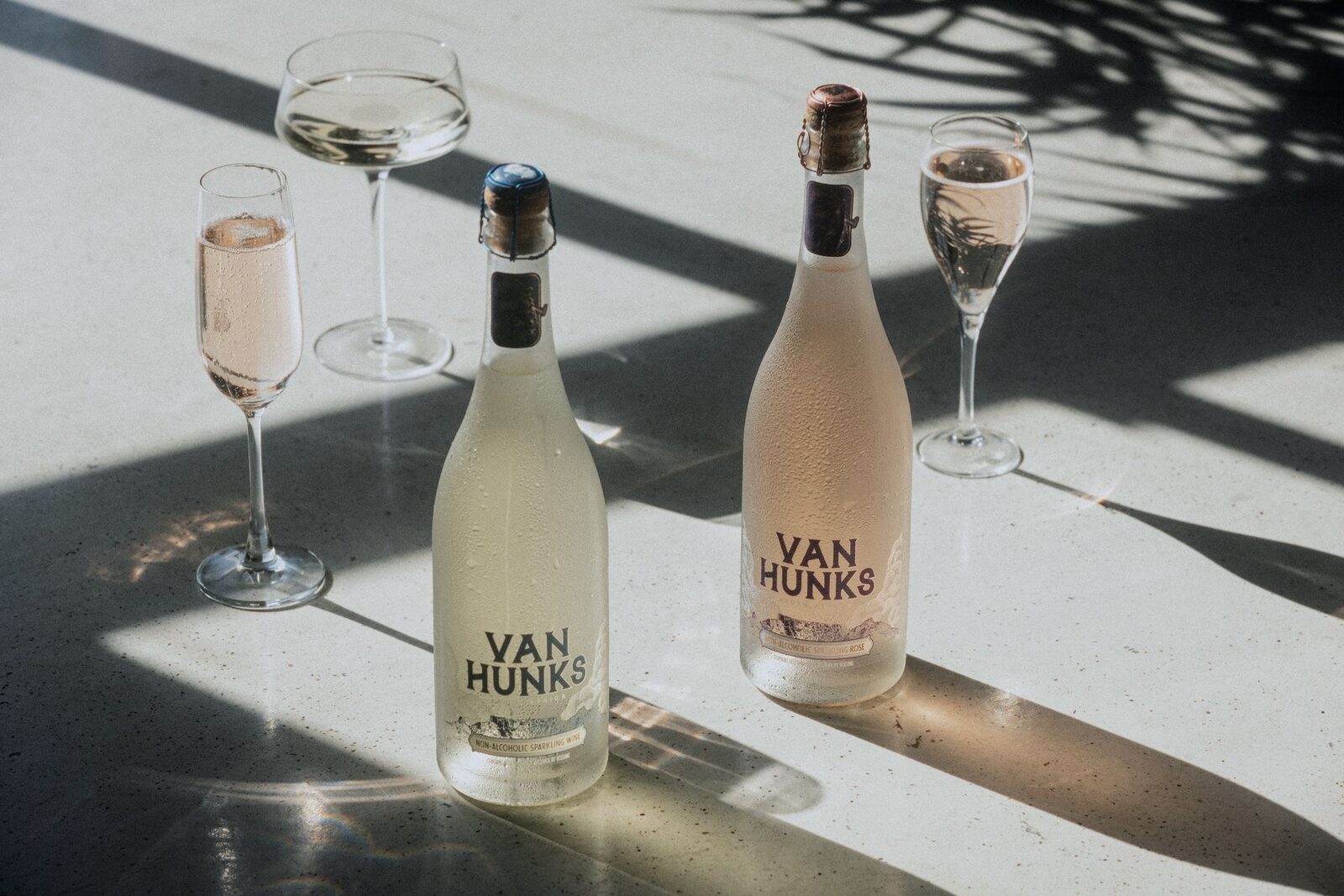 Van Hunks non-alcoholic sparkling white and rosé with two glasses in late afternoon sun
